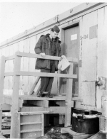 Brown examining waste discharge bucket at barracks entrance